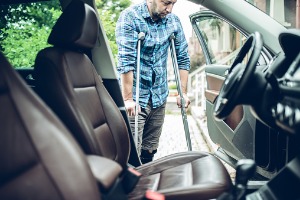 A hurt employee on crutches trying to get into a car, needing a Workers’ Compensation Attorney in Normal IL