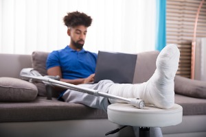 man-with-broken-leg-using-laptop-picture-id917885490